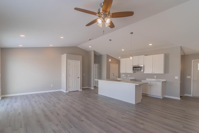 6308 Perch Dr, Weston, WI 54476 - kitchen with stainless steel microwave, lofted ceiling, white cabinetry, light wood-style flooring, and open floor plan