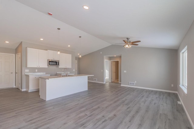 6308 Perch Dr, Weston, WI 54476 - kitchen with stainless steel microwave, a kitchen island with sink, lofted ceiling, a ceiling fan, and white cabinetry