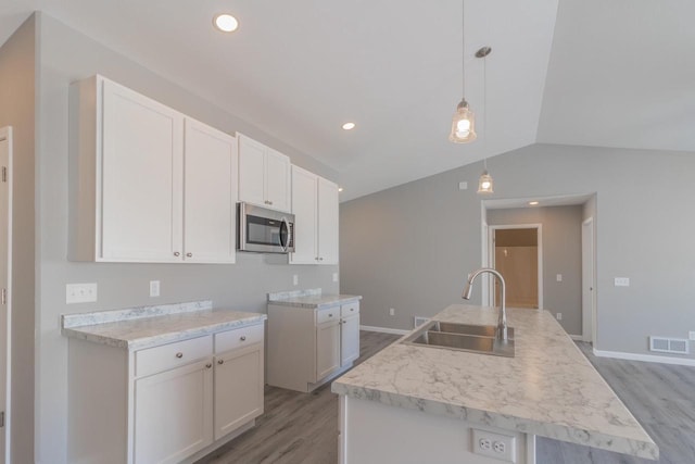 6308 Perch Dr, Weston, WI 54476 - kitchen with stainless steel microwave, light wood-type flooring, light countertops, white cabinets, and lofted ceiling