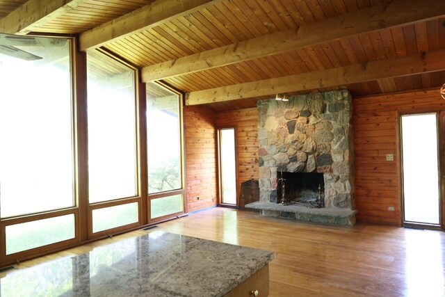 N2335 Main Rd, Lake Geneva, WI 53147 - unfurnished living room featuring wood finished floors, a stone fireplace, wood walls, and wood ceiling with exposed beams