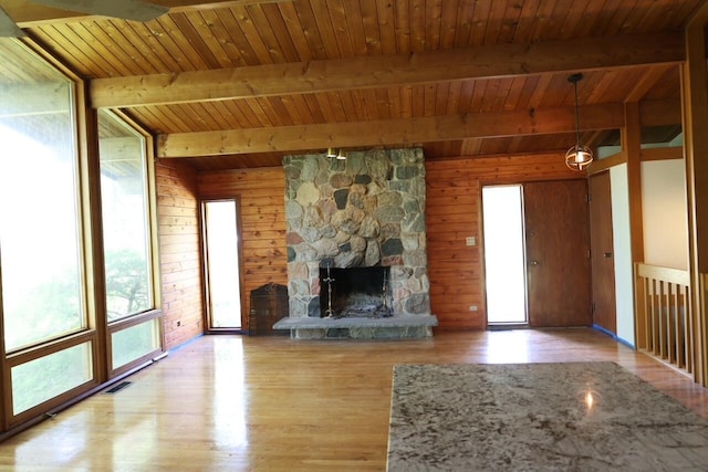 N2335 Main Rd, Lake Geneva, WI 53147 - unfurnished living room featuring wood ceiling with exposed beams, wood finished floors, a stone fireplace, and wooden walls
