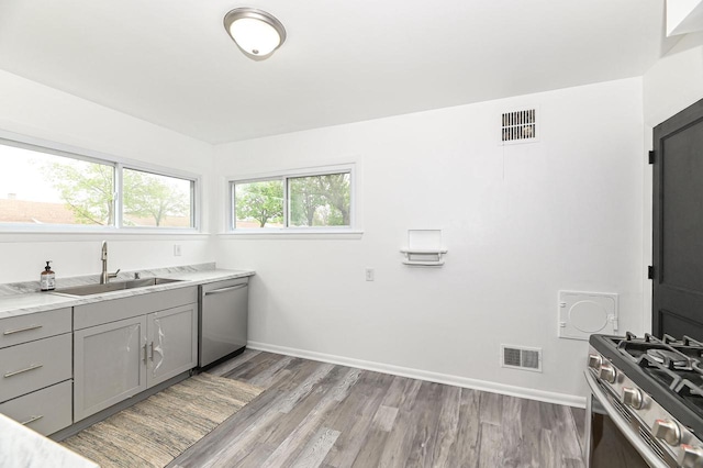 4155 N 67th St, Milwaukee, WI 53216 - kitchen featuring gray cabinets, stainless steel appliances, a sink, light wood-style flooring, and baseboards