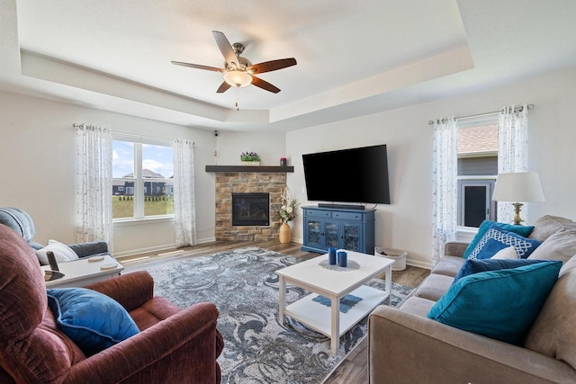 35209 Winnebago Ct, Summit, WI 53066 - living area with a tray ceiling, a ceiling fan, wood finished floors, baseboards, and a fireplace