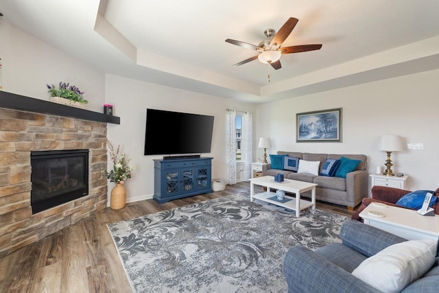 35209 Winnebago Ct, Summit, WI 53066 - living room with a ceiling fan, a stone fireplace, wood finished floors, a raised ceiling, and baseboards