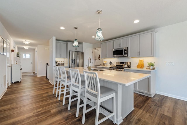 35209 Winnebago Ct, Summit, WI 53066 - kitchen with appliances with stainless steel finishes, a sink, baseboards, light countertops, and a breakfast bar area