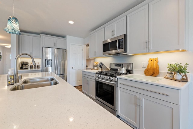 35209 Winnebago Ct, Summit, WI 53066 - kitchen featuring appliances with stainless steel finishes, a sink, light stone countertops, hanging light fixtures, and recessed lighting