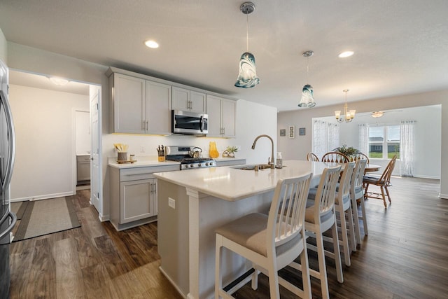 35209 Winnebago Ct, Summit, WI 53066 - kitchen featuring appliances with stainless steel finishes, a sink, dark wood-style floors, a kitchen breakfast bar, and light countertops