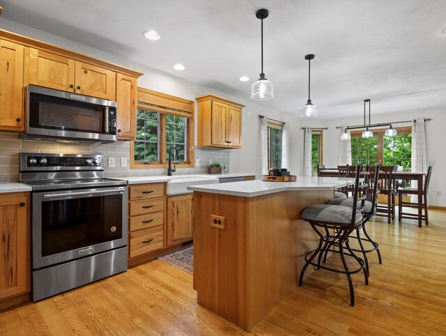 5605 N Mcnichols Dr, Milton, WI 53563 - kitchen featuring stainless steel appliances, light wood-type flooring, backsplash, a center island, and light countertops