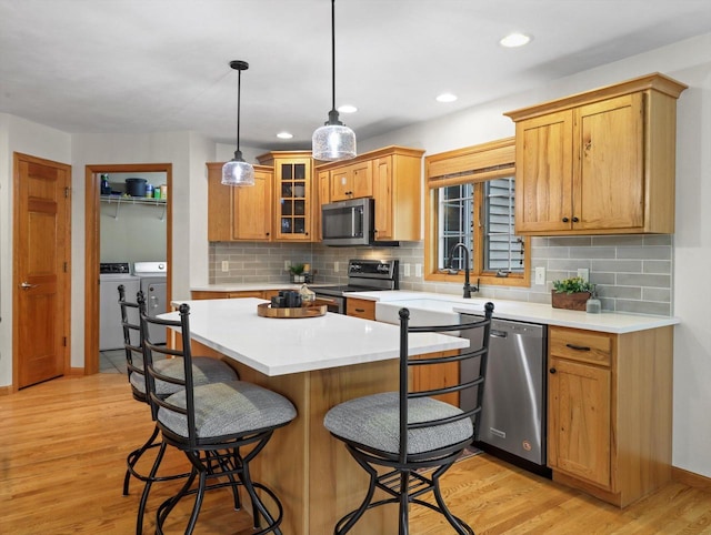 5605 N Mcnichols Dr, Milton, WI 53563 - kitchen with appliances with stainless steel finishes, separate washer and dryer, a kitchen bar, decorative backsplash, and light countertops
