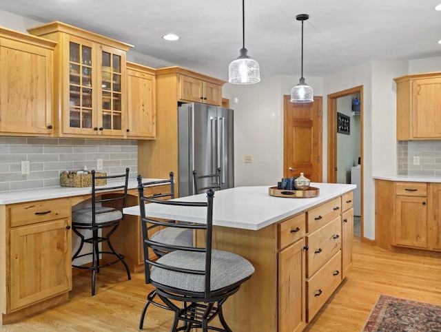5605 N Mcnichols Dr, Milton, WI 53563 - kitchen with freestanding refrigerator, decorative backsplash, a breakfast bar, light wood-type flooring, and glass insert cabinets
