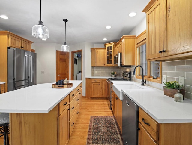 5605 N Mcnichols Dr, Milton, WI 53563 - kitchen with appliances with stainless steel finishes, light wood-style flooring, a center island, backsplash, and glass insert cabinets