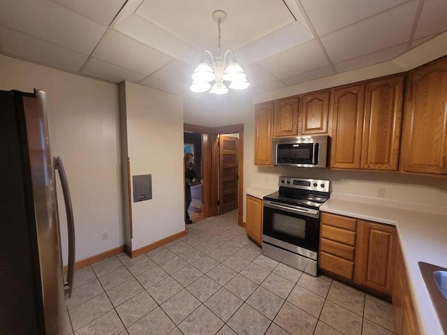 324 N Pine St, Reedsburg, WI 53959 - kitchen with stainless steel appliances, a chandelier, brown cabinetry, light countertops, and light tile patterned floors