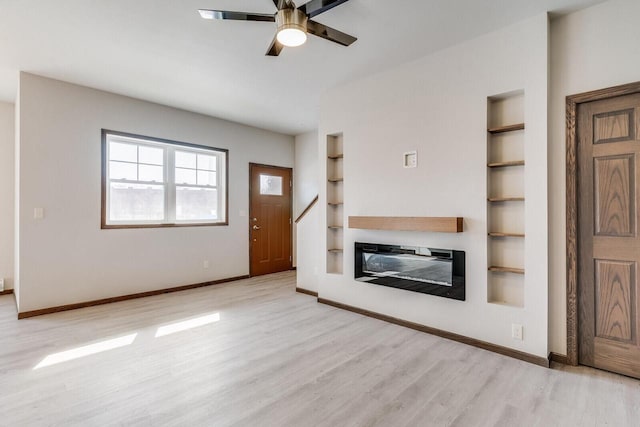 1325 Hagar St, La Crosse, WI 54603 - unfurnished living room featuring built in features, wood finished floors, baseboards, ceiling fan, and a glass covered fireplace