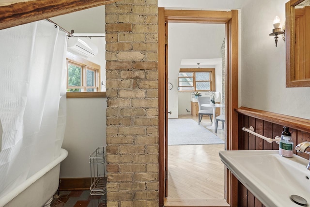 2710 N Hackett Ave, Milwaukee, WI 53211 - bathroom with healthy amount of natural light, a wall mounted AC, a freestanding tub, and wood finished floors