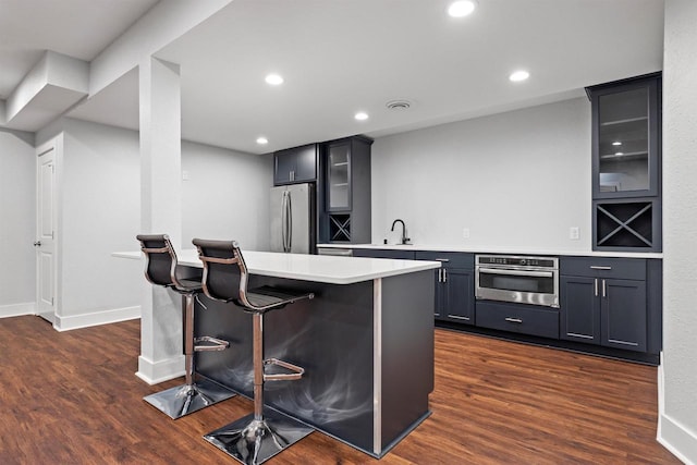 19750 Heron Pass, Brookfield, WI 53045 - kitchen featuring appliances with stainless steel finishes, glass insert cabinets, a breakfast bar, light countertops, and dark wood-style flooring