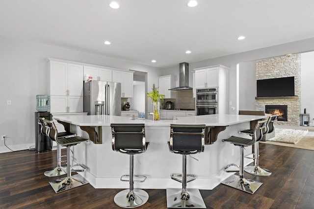 19750 Heron Pass, Brookfield, WI 53045 - kitchen with appliances with stainless steel finishes, wall chimney range hood, a large island, a fireplace, and light countertops