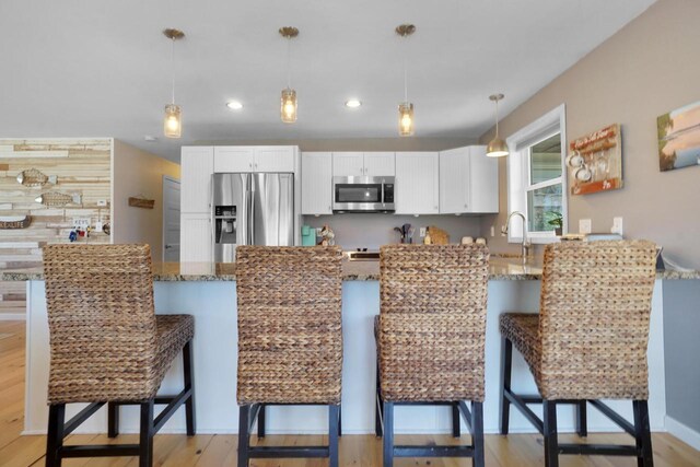 1014 Long Bow Ct, Nekoosa, WI 54457 - kitchen with stainless steel appliances, light stone counters, a peninsula, a breakfast bar area, and recessed lighting