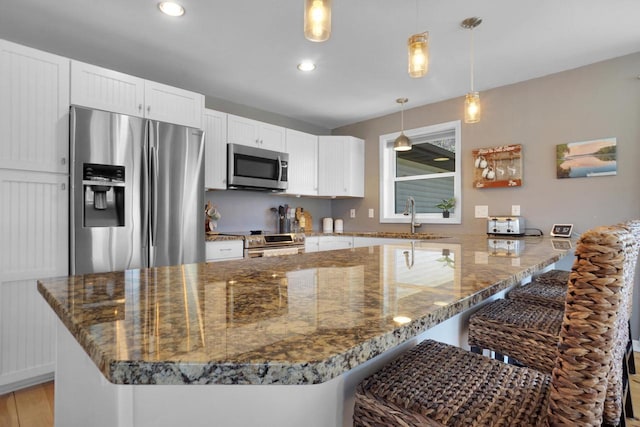 1014 Long Bow Ct, Nekoosa, WI 54457 - kitchen featuring stainless steel appliances, dark stone counters, a kitchen breakfast bar, white cabinetry, and recessed lighting