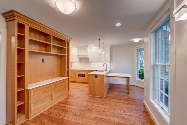 2818 Marshall Ct, Madison, WI 53705 - kitchen featuring a sink, wall oven, decorative backsplash, a kitchen breakfast bar, and light wood finished floors