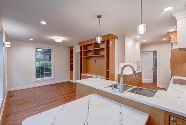2818 Marshall Ct, Madison, WI 53705 - kitchen featuring a sink, wood finished floors, hanging light fixtures, white cabinets, and baseboards