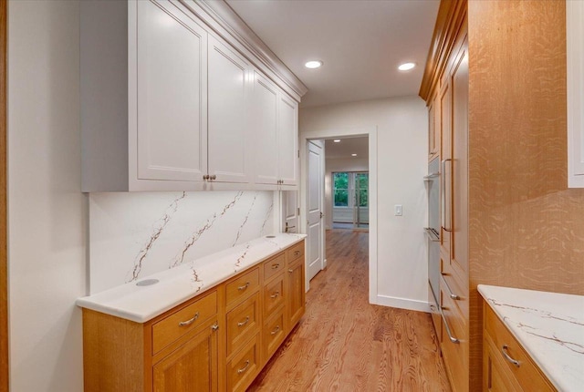 2818 Marshall Ct, Madison, WI 53705 - kitchen with light wood finished floors, recessed lighting, tasteful backsplash, white cabinets, and light stone counters