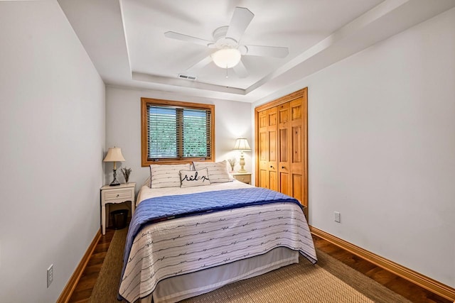 W375S4961 E Pretty Lake Rd, Dousman, WI 53118 - bedroom featuring a tray ceiling, wood finished floors, baseboards, a ceiling fan, and a closet