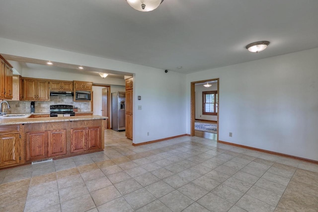 W1041 County Road O, Oconomowoc, WI 53066 - kitchen with black appliances, a sink, under cabinet range hood, baseboards, and a peninsula