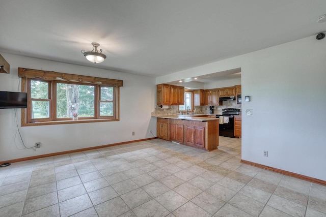 W1041 County Road O, Oconomowoc, WI 53066 - kitchen featuring black range with electric stovetop, baseboards, a peninsula, and brown cabinets