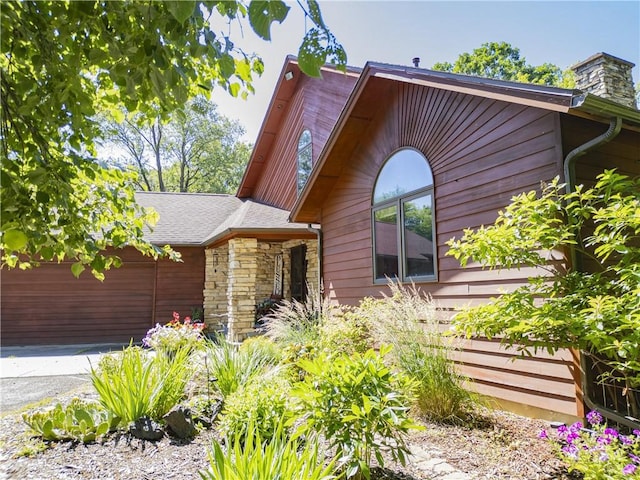 18845 64th Ave, Chippewa Falls, WI 54729 - view of side of property with stone siding, an attached garage, a chimney, and driveway
