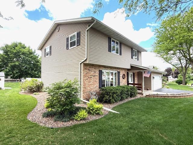 417 Raintree Dr, Fort Atkinson, WI 53538 - view of front facade with brick siding, a garage, and a front lawn