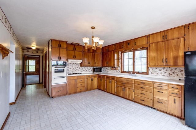 4884 Brewery Rd, Cross Plains, WI 53528 - kitchen with white appliances, a warming drawer, a chandelier, under cabinet range hood, and brick patterned flooring