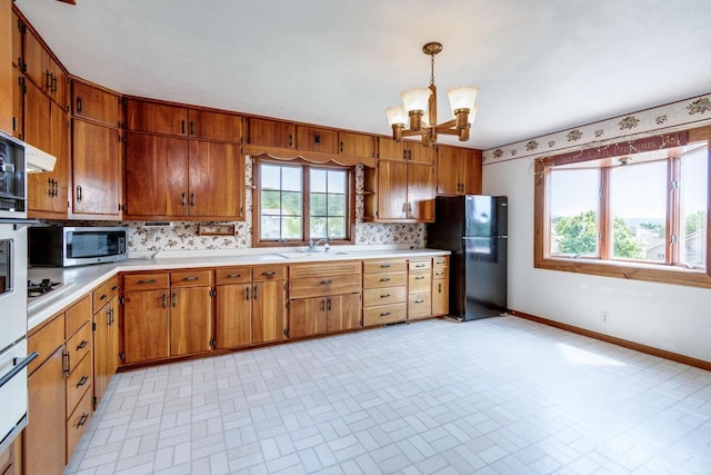 4884 Brewery Rd, Cross Plains, WI 53528 - kitchen featuring freestanding refrigerator, a chandelier, stainless steel microwave, light countertops, and baseboards
