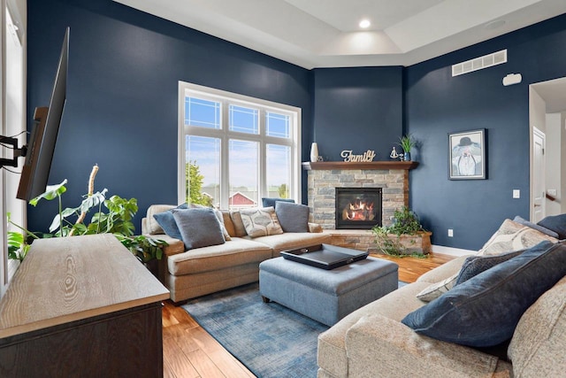 3403 Whistling Wind Way, Sun Prairie, WI 53590 - living room featuring wood finished floors, a high ceiling, a stone fireplace, and a raised ceiling