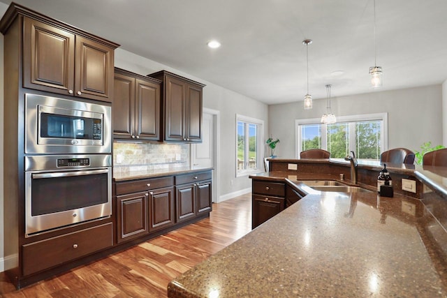 3403 Whistling Wind Way, Sun Prairie, WI 53590 - kitchen featuring stainless steel appliances, tasteful backsplash, dark brown cabinets, dark stone countertops, and recessed lighting