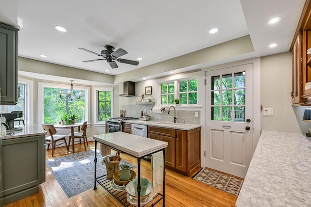 933 Juneau Dr, Fontana, WI 53125 - kitchen featuring wall chimney range hood, a sink, appliances with stainless steel finishes, healthy amount of natural light, and recessed lighting