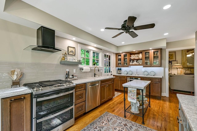 933 Juneau Dr, Fontana, WI 53125 - kitchen with wall chimney exhaust hood, appliances with stainless steel finishes, open shelves, a sink, and brown cabinets