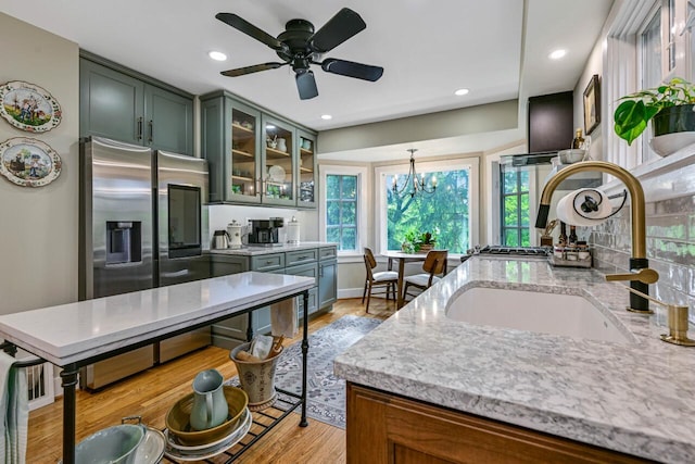 933 Juneau Dr, Fontana, WI 53125 - kitchen featuring a sink, light stone counters, light wood-type flooring, recessed lighting, and glass insert cabinets