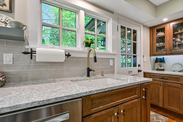 933 Juneau Dr, Fontana, WI 53125 - kitchen with a sink, brown cabinets, backsplash, glass insert cabinets, and light stone counters
