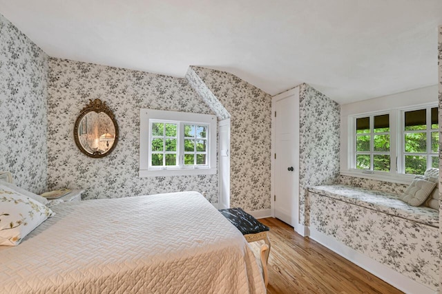 933 Juneau Dr, Fontana, WI 53125 - bedroom with wood finished floors, wallpapered walls, multiple windows, vaulted ceiling, and baseboards