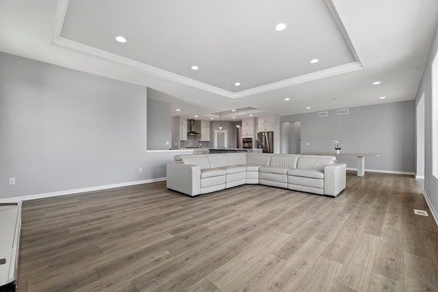 1279 E Hickory Creek Ct, Oak Creek, WI 53154 - living room with a tray ceiling, light wood-style floors, baseboards, recessed lighting, and ornamental molding