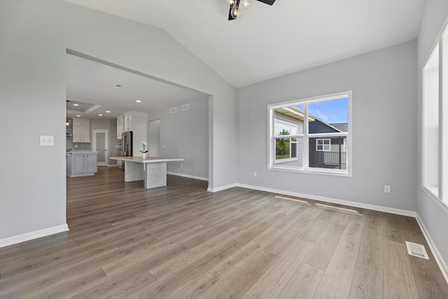 1279 E Hickory Creek Ct, Oak Creek, WI 53154 - unfurnished living room with wood finished floors, lofted ceiling, baseboards, and ceiling fan