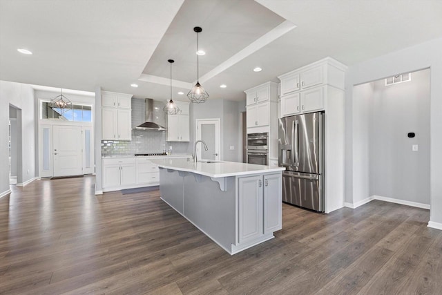 1279 E Hickory Creek Ct, Oak Creek, WI 53154 - kitchen featuring appliances with stainless steel finishes, wall chimney range hood, a raised ceiling, a sink, and tasteful backsplash