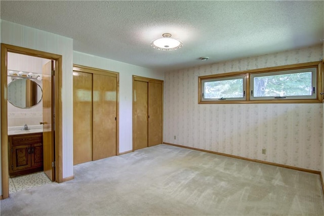 8303 163rd St, Chippewa Falls, WI 54729 - unfurnished bedroom featuring multiple closets, carpet, ensuite bathroom, and a textured ceiling