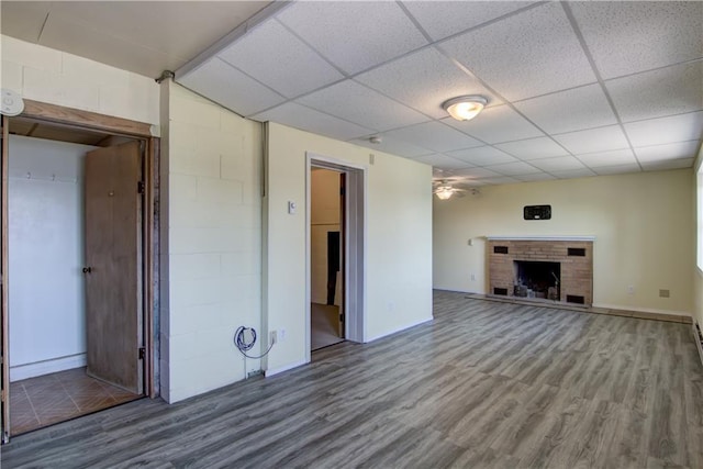 8303 163rd St, Chippewa Falls, WI 54729 - unfurnished living room featuring wood finished floors, a ceiling fan, a drop ceiling, and a brick fireplace
