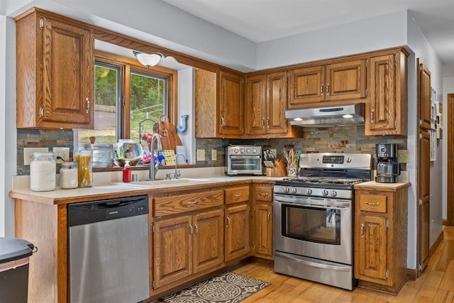S69W32641 Westgate Dr, Mukwonago, WI 53149 - kitchen with stainless steel appliances, under cabinet range hood, light countertops, and brown cabinetry