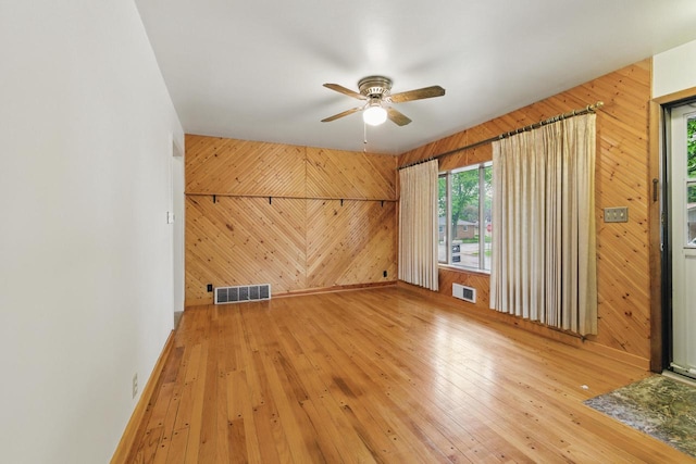 2507 S 94th St, West Allis, WI 53227 - unfurnished living room featuring wood walls, wood-type flooring, a ceiling fan, and baseboards