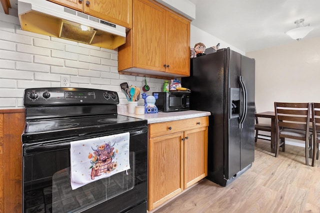 1413 E Marquette St, Appleton, WI 54911 - kitchen with black appliances, under cabinet range hood, light wood-style floors, light countertops, and decorative backsplash