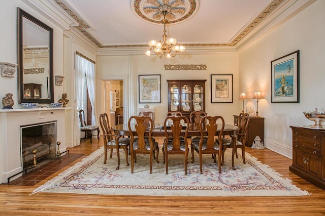 150 Rountree Ave, Platteville, WI 53818 - dining area with a chandelier, wood finished floors, crown molding, a tile fireplace, and baseboards