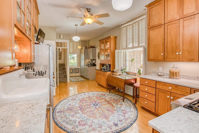 150 Rountree Ave, Platteville, WI 53818 - kitchen with light wood-style flooring, ceiling fan, brown cabinets, and glass insert cabinets