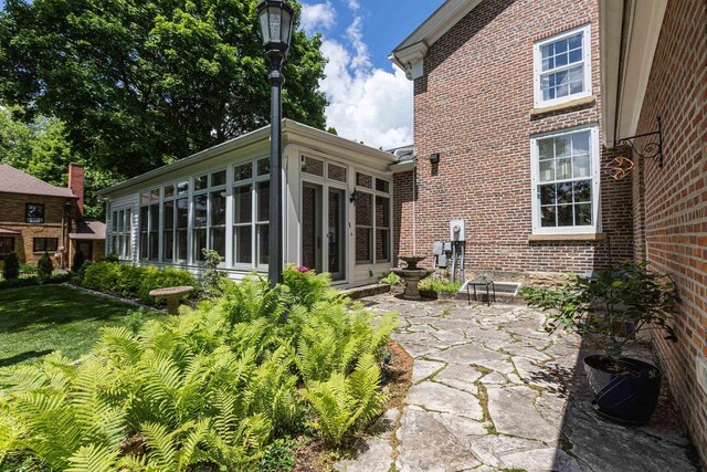 150 Rountree Ave, Platteville, WI 53818 - rear view of house featuring a sunroom, brick siding, a patio area, and a yard
